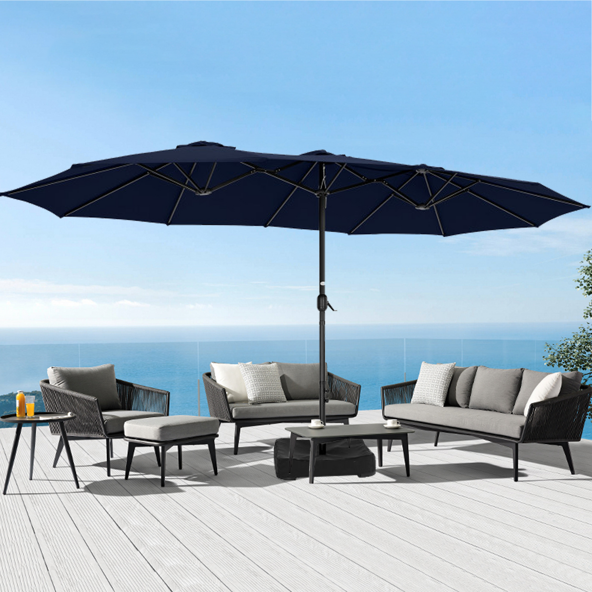Patioslife Horizon Haven double-sided patio umbrella with base in black, 4.6 x 2.7m, shading a modern outdoor sofa set on an ocean-view deck
