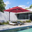 Patioslife 3x3m Burgundy LED cantilever umbrella shading poolside sun loungers beside a modern home
