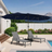 Patioslife Horizon Haven double-sided patio umbrella with base in black, 4.6 x 2.7m, with LED lights over two poolside loungers in a backyard