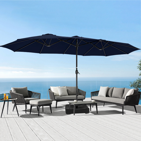 Patioslife Horizon Haven double-sided patio umbrella with base in black, 4.6 x 2.7m, shading a modern outdoor sofa set on an ocean-view deck