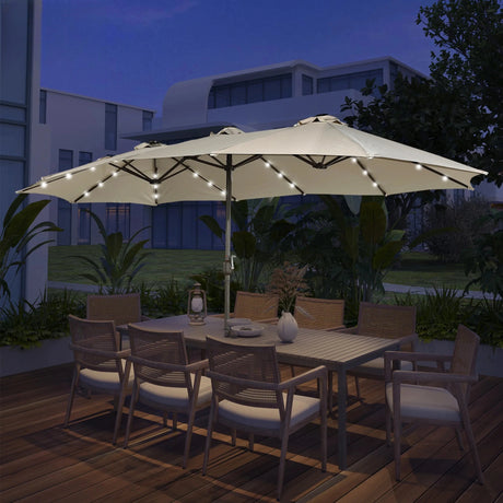 Patioslife Horizon Haven double-sided patio umbrella with base in cream, 4.6 x 2.7m, with LED lights over an outdoor dining set at night
