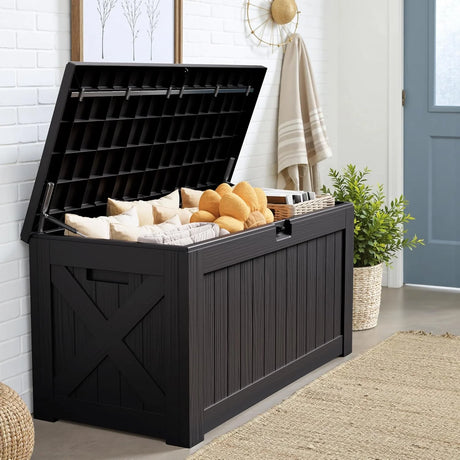 Outdoor deck box with open lid storing cushions and pool towels, large black resin weatherproof patio storage box