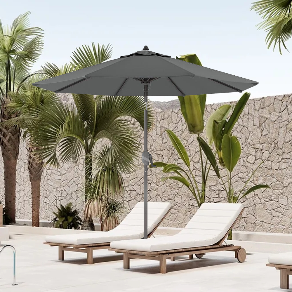 Patioslife Solara charcoal market umbrella shading sun loungers beside a tropical stone wall pool area