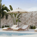 Patioslife Solara cream market umbrella shading poolside loungers with tropical plants and stone wall backdrop