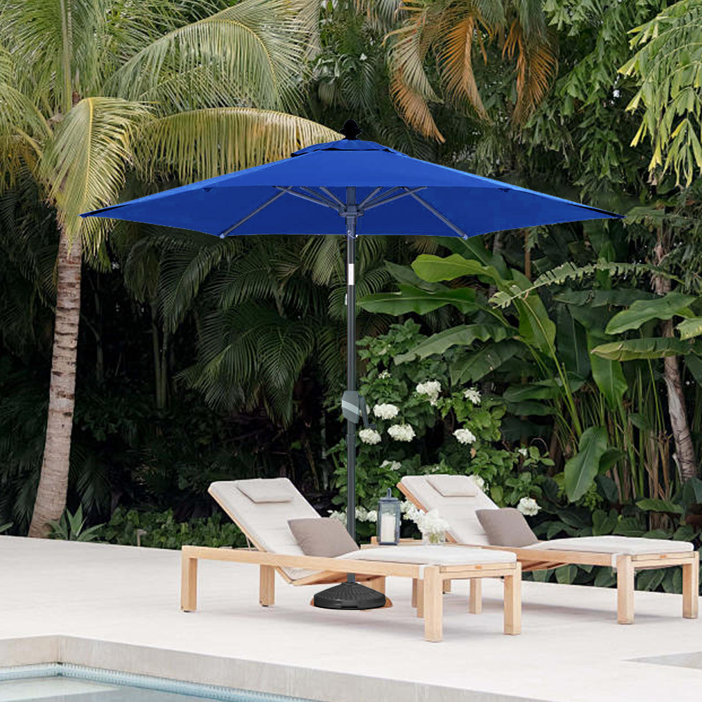 Patioslife Solara navy blue market umbrella beside a tropical pool with wooden loungers and lush greenery