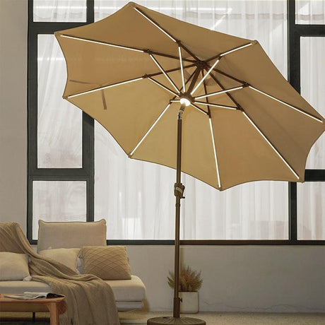 Patioslife Solara tan market umbrella with illuminated ribs beside a relaxed indoor outdoor lounge space