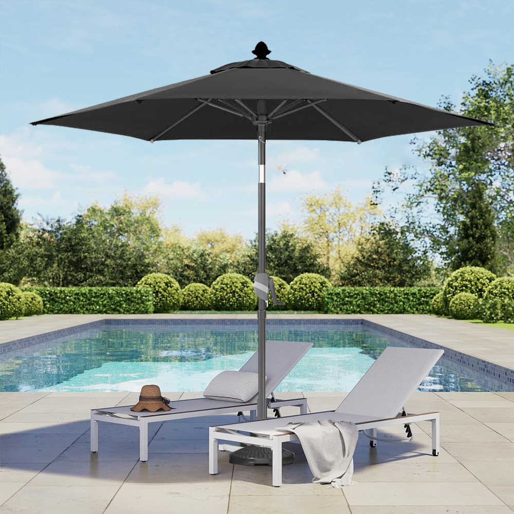 Patioslife Solara blackmarket umbrella beside a swimming pool with white sun loungers and garden greenery