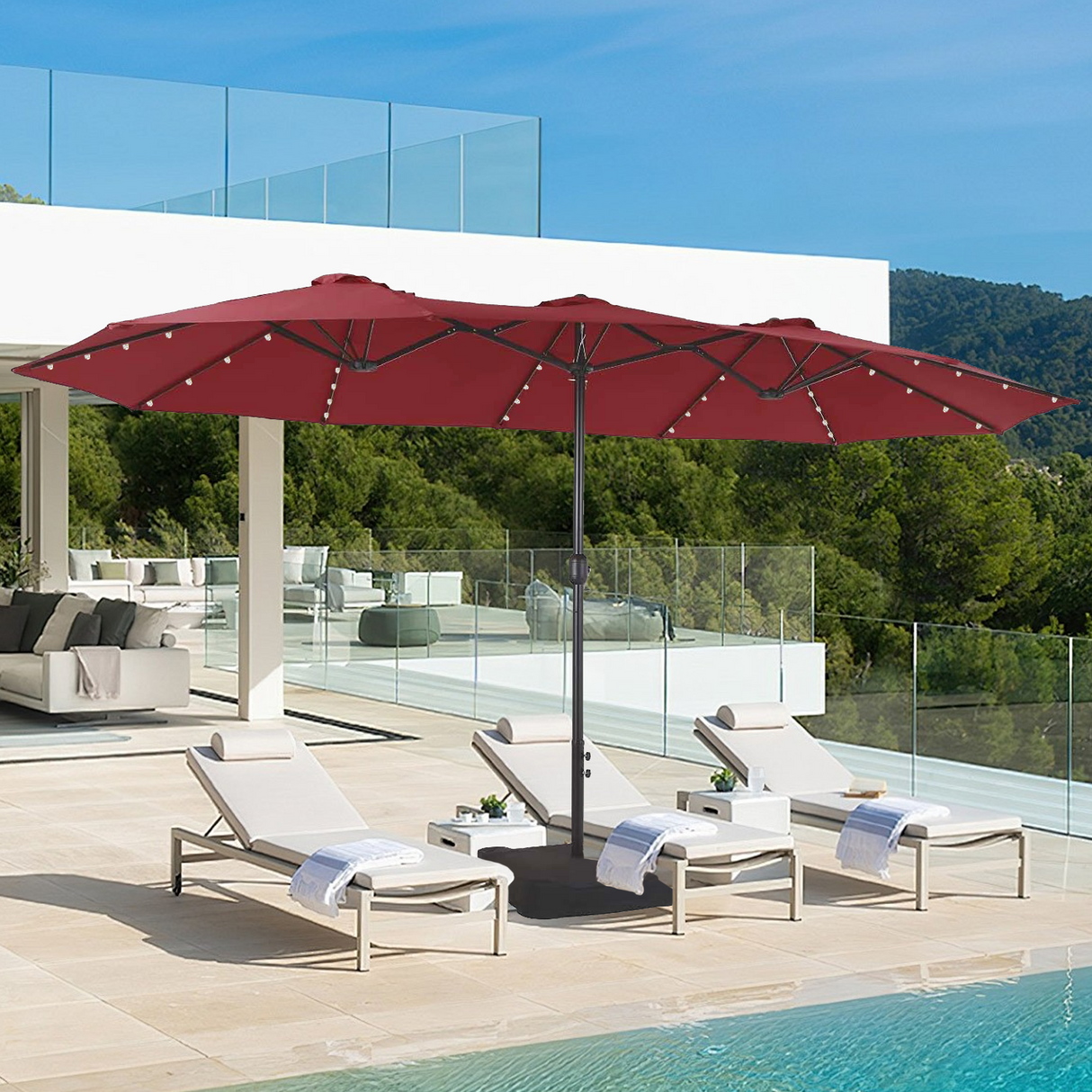 Patioslife Horizon Haven double-sided patio umbrella with base in red, 4.6 x 2.7m,with LED lights shading pool loungers beside a modern white villa